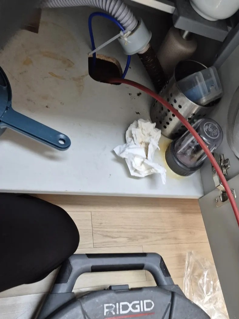 광명동 싱크대막힘 작업으로 하부장 바닥 배수구에 스프링 케이블을 넣는 모습