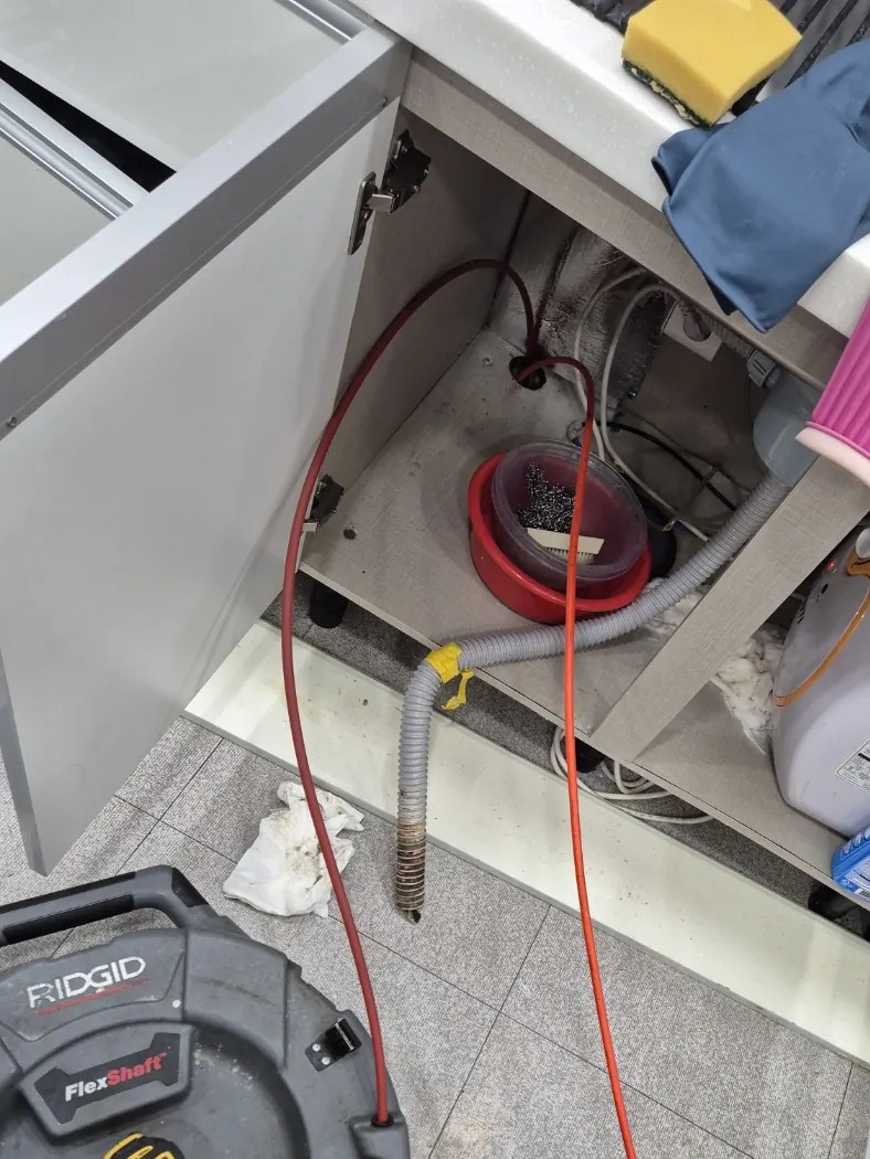 정자동 싱크대막힘 작업으로 하부장에서 빼낸 주름관과 벽 쪽 배수구에 넣은 장비 줄