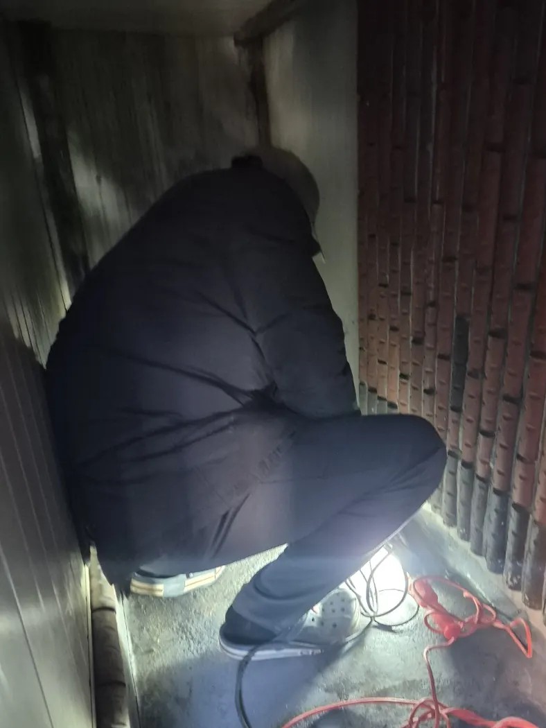 정자동 하수구막힘 건물 옆 좁은 통로에서 조명을 켜고 배관 작업하는 모습